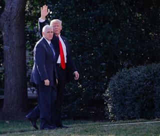 マイク・ペンス副大統領（左）とともに、ホワイトハウスに向かう途中、報道陣に手を振るドナルド・トランプ大統領＝２５日、米ワシントン（ＡＰ）