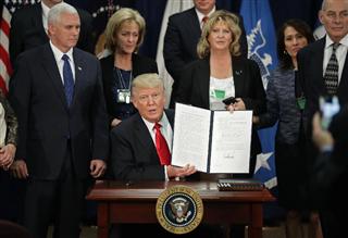 ２５日、ワシントンの国土安全保障省で、署名した大統領令を見せるトランプ米大統領（ゲッティ＝共同）