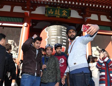 雷門の前で記念撮影する外国人観光客。日本は２０２０年、年間４０００万人の訪日外国人観光客を誘致する計画だ＝今年１月、東京都台東区