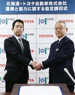 協定調印式で北海道の土屋俊亮農政部長（右）と握手するトヨタ自動車の秦直道・新事業企画部長＝２２日午後、北海道庁