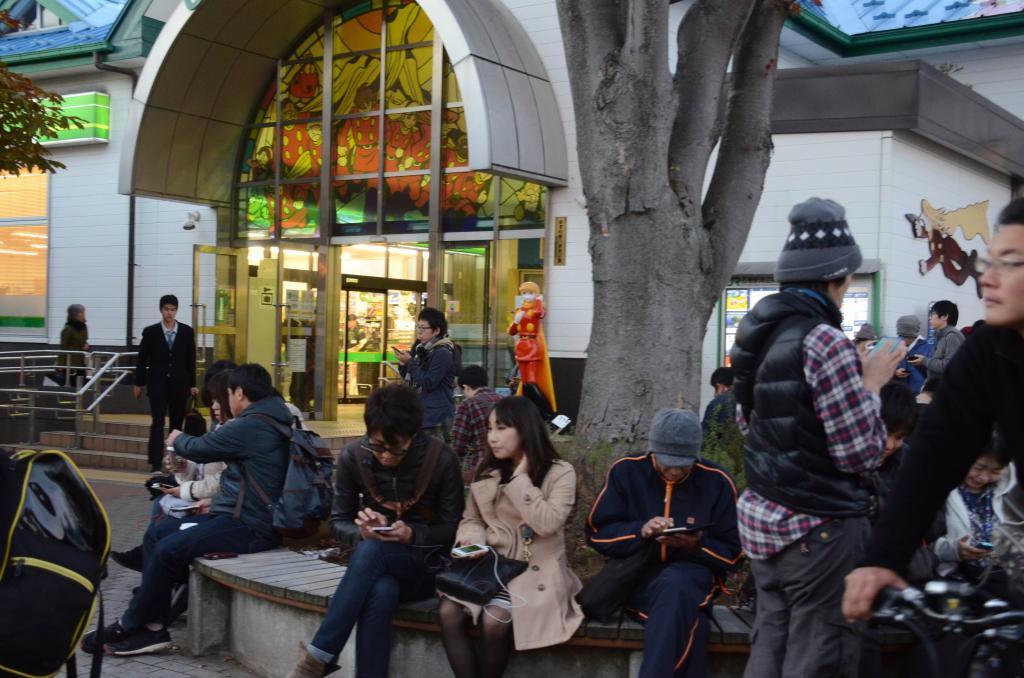 ＪＲ石巻駅前で遅くまでスマホを片手に「ポケモンＧＯ」で遊ぶ人たち＝宮城県石巻市