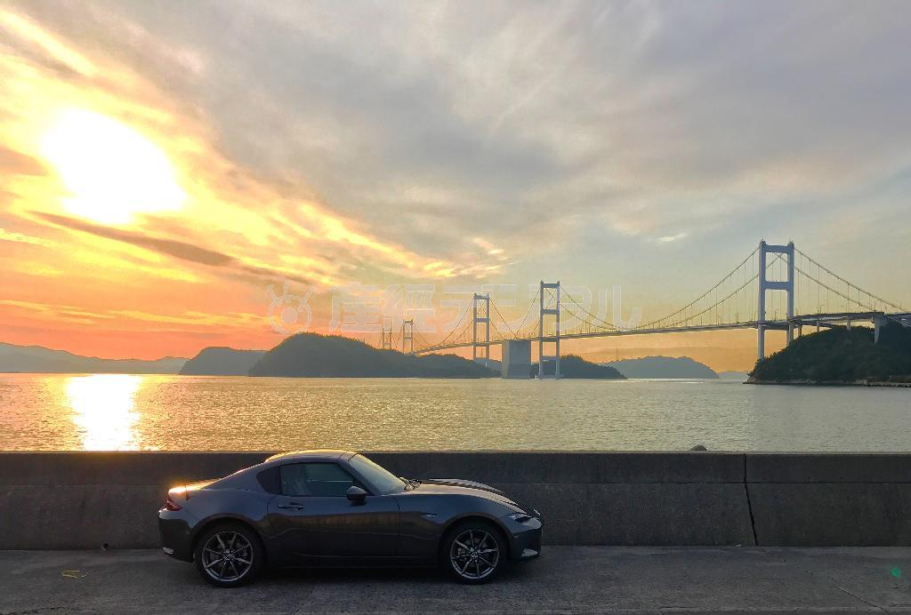 瀬戸内の夕日としまなみ海道の来島海峡大橋を背に、横顔を浮かび上がらせるロードスターＲＦ（ｉＰｈｏｎｅで撮影）