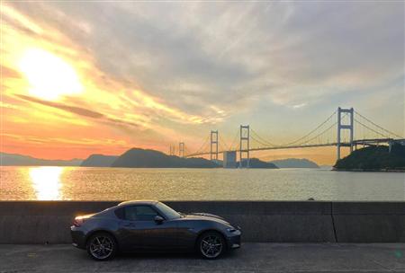 瀬戸内の夕日としまなみ海道の来島海峡大橋を背に、横顔を浮かび上がらせるロードスターＲＦ（ｉＰｈｏｎｅで撮影）