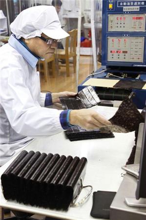 乾燥させたノリに破れなどがないか調べる加工工場の従業員＝１月、佐賀市