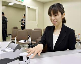 指の静脈データを照合する生体認証で、預金を出し入れできるサービスの実演をする山口ＦＧの社員＝６日、山口県下関市