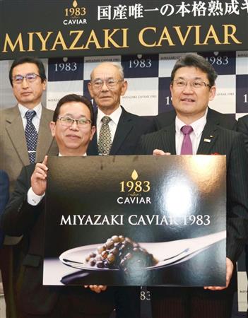 国産キャビアが初輸出された宮崎空港での記念式典で、パネルを手にするジャパンキャビアの坂元基雄社長（左）と河野俊嗣宮崎県知事（右）＝８日、宮崎市