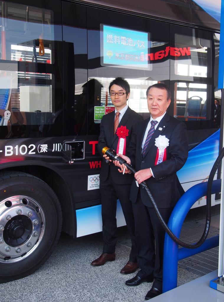燃料電池バスに充填する岩谷産業の野村雅男社長（右）＝１６日、東京都江東区