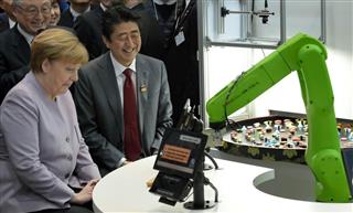 「ＣｅＢＩＴ２０１７」の会場で、すしを運ぶロボットを見学する安倍晋三首相とドイツのメルケル首相＝２０日、ハノーバー（ＡＰ）
