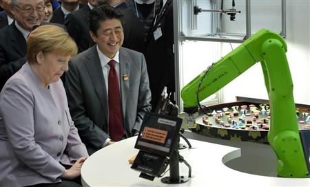 「ＣｅＢＩＴ２０１７」の会場で、すしを運ぶロボットを見学する安倍晋三首相とドイツのメルケル首相＝２０日、ハノーバー（ＡＰ）