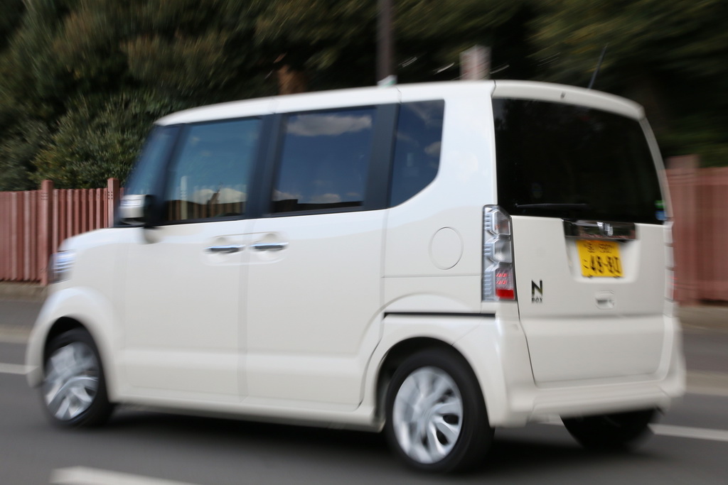 斜め後ろからホンダ「Ｎ－ＢＯＸ」を眺める（法定速度で走行していますが、流動感を出すために低速でシャッターを切っています）