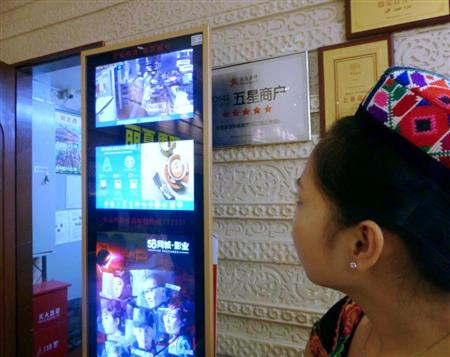 上海市の飲食店の入り口で、厨房内の様子を映した画面を見る女性従業員（共同）