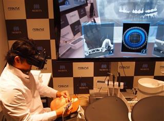 ソフトバンク子会社などが開発した、ＭＲ（複合現実）を使った歯科医療支援システムのデモ。後ろの画面には、ゴーグル型端末を通して見ている光景が映し出されている＝２１日、東京都江東区