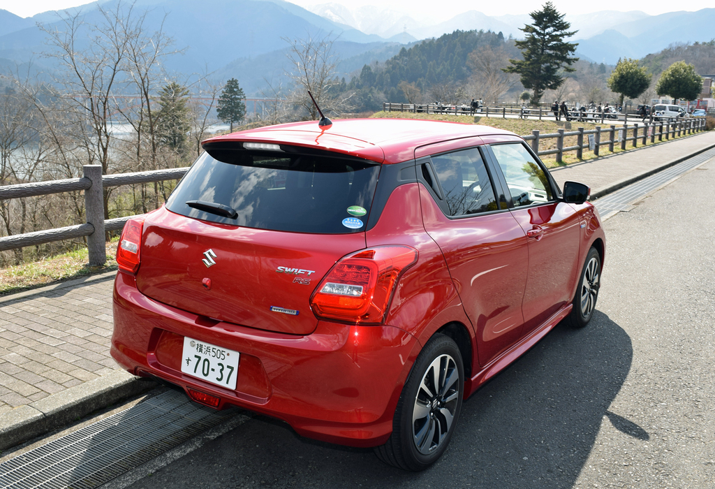 スイフトのリヤビュー。塗装の陰影感もきれい。奥にはバイクツーリング中に休憩する人たちの姿も