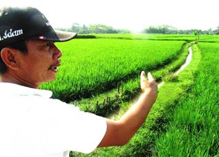 インドネシア西ジャワ州ワナカルタ村で、中国が受注した高速鉄道の「建設予定地」を指さす地主のイダムさん（吉村英輝撮影）