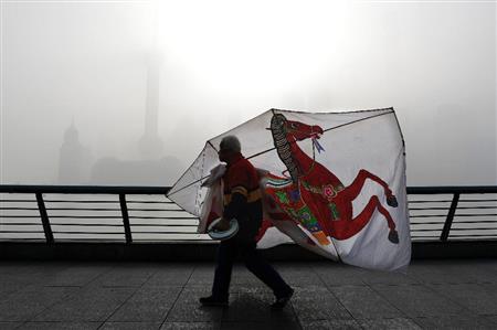 中国・上海の浦東新区（経済特区）で、たこを持って歩く男性。背後にはスモッグで見えなくなった特区のビルが＝２０１６年４月（ＡＰ）