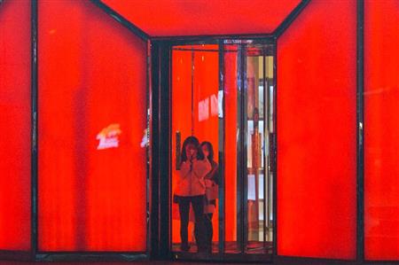 大気汚染警報が出た中国でマスクを顔に当てて外に出る女性＝２０１６年１２月、北京（ＡＰ）