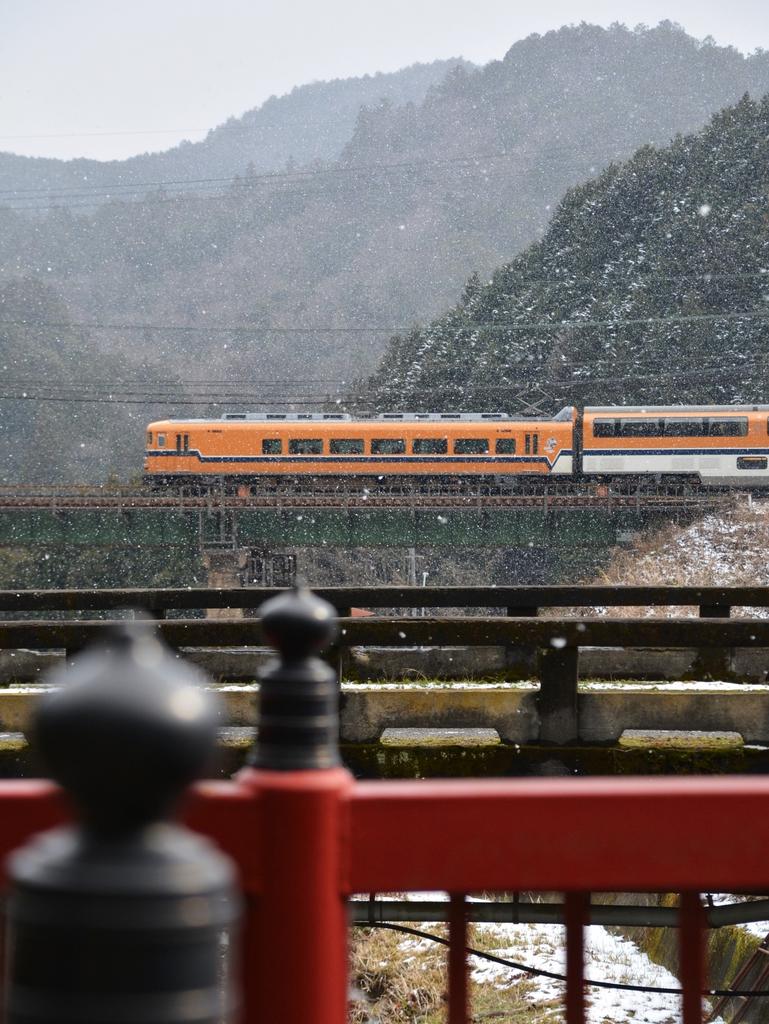 白鳥神社に渡る橋の欄干越しにオレンジの特急が駆け抜けた＝奈良県宇陀市（三本松－室生口大野）