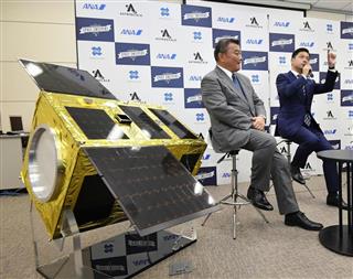 記者会見するアストロスケールの岡田光信ＣＥＯ（右）とＡＮＡホールディングスの長峯豊之副社長。左は宇宙ごみ除去衛星の模型＝１４日午後、東京都千代田区