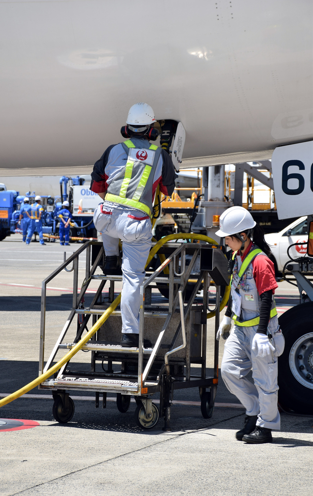 前輪付近で電源コネクタを差し込むスタッフ。これは地上から電源を供給するための作業。これにより駐機中は航空機のエンジンを作動しなくても機内の照明や電子機器などが使えるようになる