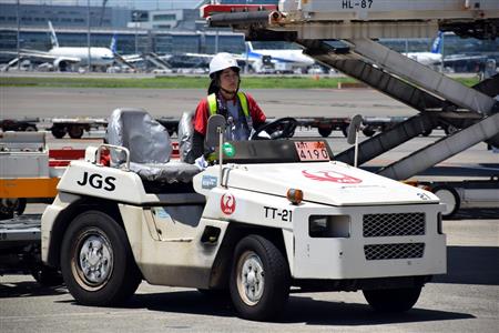 トーイングトラクターでコンテナを運ぶ酒井さん