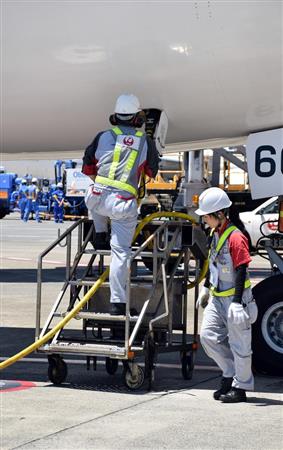 前輪付近で電源コネクタを差し込むスタッフ。これは地上から電源を供給するための作業。これにより駐機中は航空機のエンジンを作動しなくても機内の照明や電子機器などが使えるようになる