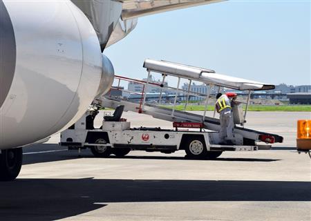 搭乗が遅れた乗客の手荷物をベルトローダーで積み込むグランドスタッフ
