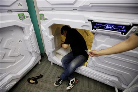 中国・北京に作られた昼寝専用のカプセルホテルで休もうとする男性。耳栓を手渡されようとしている。中国には昼寝の習慣があるほか、ホワイトカラーの過重労働が深刻な問題となっており、このカプセルホテルは拡大を続ける「シェアリング・エコノミー」の一種として注目を集めているようだ（ロイター）