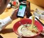 損保ジャパン日本興亜ひまわり生命保険のアプリを使い、昼食のラーメンを撮影する男性