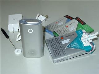 ブリティッシュ・アメリカン・タバコの「glo（グロー）」。本体（中央）上部のふたをスライドさせて開口部に専用たばこを差し、本体正面のボタンを押して加熱する。