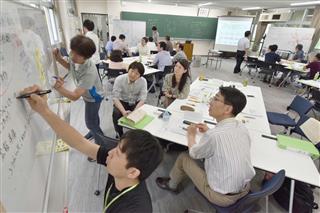 ホワイトボードを使い、サイバー攻撃への対応演習を行う合宿参加者ら＝６月、東京都調布市