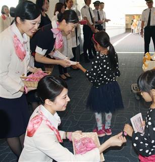 子供たちにピンク色のアームバンドを配る日航のスタッフら＝２９日午前、羽田空港