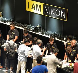 ニコン１００周年ファンミーティングで製品を介し来場者（手前）と交流するニコン社員＝大阪市福島区(奥清博撮影)