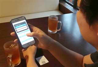 スマホを使って、自分の席から料理や飲み物を注文する客 スマホを使って、自分の席から料理や飲み物を注文する客