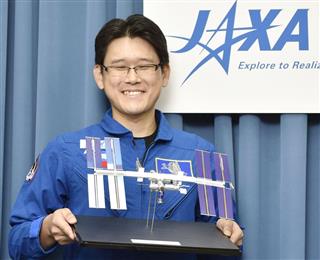 笑顔で国際宇宙ステーションの模型を持つ金井宣茂さん＝２０１５年８月、東京都千代田区