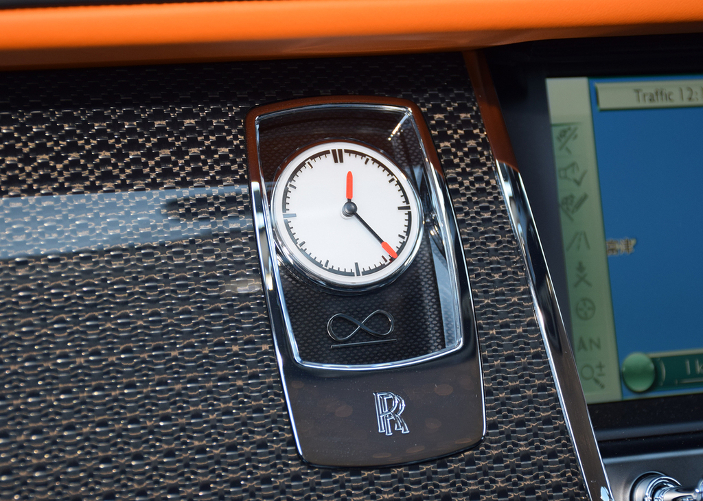 オレンジ色の針先がお洒落なアナログ時計。ダッシュボードはアルミニウムをカーボン素材に織り込んだコンポジット材を使用