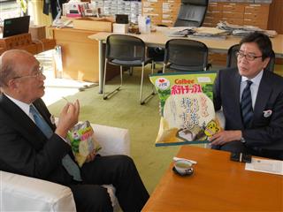 柿の葉すし味のポテチを試食する荒井正吾・奈良県知事（左）とカルビーの伊藤秀二社長＝奈良市の県庁
