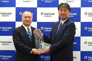 クラリベイト・アナリティクス・ジャパンの日野博文社長（左）から記念のトロフィーを受け取る富士電機の近藤史郎技術開発本部長＝東京都港区