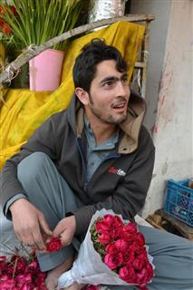 バレンタインデーの贈り物用のバラの花束を作る男性＝９日、パキスタン首都イスラマバードの路上（共同）