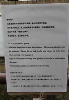 一軒家の前に掲げられた看板。中国語と英語、日本語で違法民泊であることを説明している＝昨年１１月８日、京都市右京区