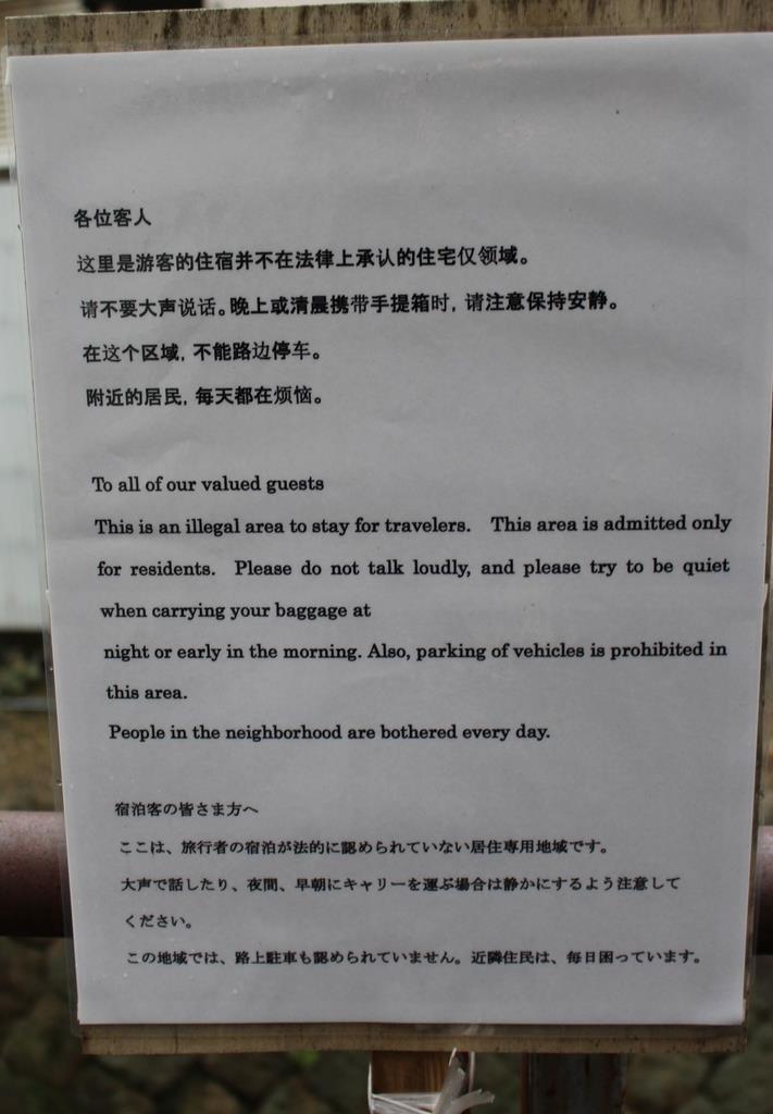 一軒家の前に掲げられた看板。中国語と英語、日本語で違法民泊であることを説明している＝昨年１１月８日、京都市右京区