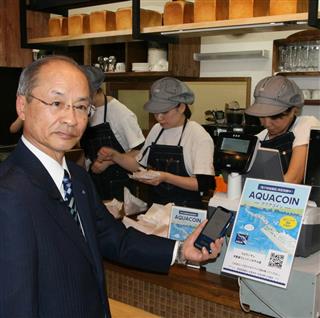 スマートフォンにダウンロードしたアクアコインのアプリを使用して買い物を行ってみせる君津信用組合の宮沢義夫理事長＝木更津市内（永田岳彦撮影）