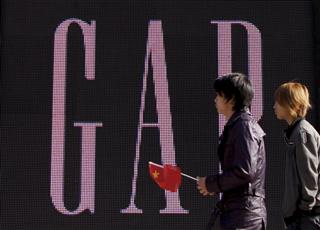 北京市内の「ギャップ」の旗艦店前で中国国旗を手に歩く男性＝２０１０年１１月１６日（ＡＰ）