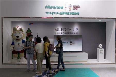 中国の電機メーカー「海信」のテレビの展示ブースの前を通り過ぎる人たち＝１５日、中国・上海の家電見本市「ＣＥＳ（コンシューマー・エレクトリック・ショー）」で（ＡＰ）