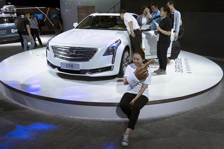 キャデラックの「ＣＴ６」の前でポーズをとって、記念撮影する女性＝１５日、中国・上海の「ＣＥＳ（コンシューマー・エレクトロニック・ショー）」で（ＡＰ）