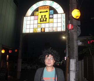 明かりを取り戻した泉町仲通り商店街の門看板と加藤雅史さん＝水戸市泉町