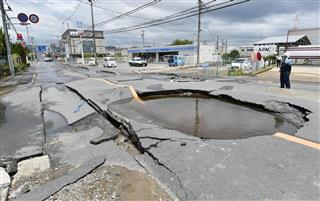 地震で水道管が破裂し陥没した道路＝１８日、大阪府高槻市