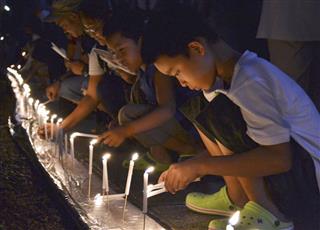 高野山奥の院の参道で、ろうそくに火をともす子供＝１３日夜、和歌山県高野町