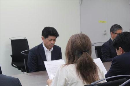陳情書を読み上げる田久保真紀さん(後ろ姿)と、それを聞く資源エネルギー庁の山崎琢矢・新エネルギー課長=22日、東京都千代田区の経済産業省(三枝玄太郎撮影)