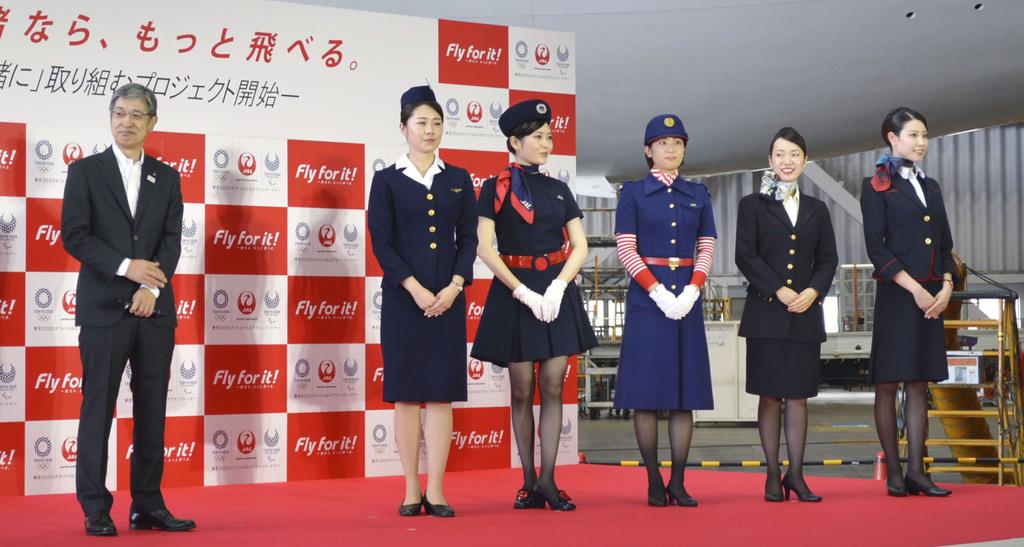 記者会見する日本航空の赤坂祐二社長（左端）と歴代の制服を着た客室乗務員ら＝２３日、東京都大田区