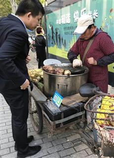 スマートフォン決済用の「ＱＲコード」を掲げている中国・上海市内の焼き芋の露店（河崎真澄撮影）